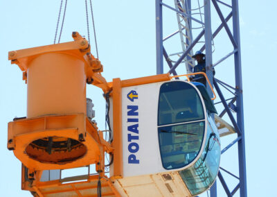 The slew ring and operator cab of a Potain MDT 178 being lowered during a dismantling.